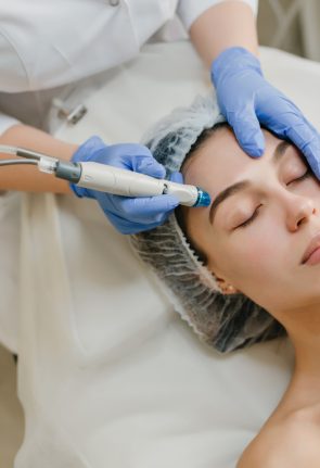 View from above rejuvenation of beautiful woman enjoying cosmetology procedures in beauty salon. Dermatology, hands in blue glows, healthcare, therapy, botox